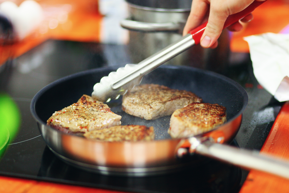 a-chef-flipping-pork-cuts-that-are-cooking-in-a-non-stick-pan
