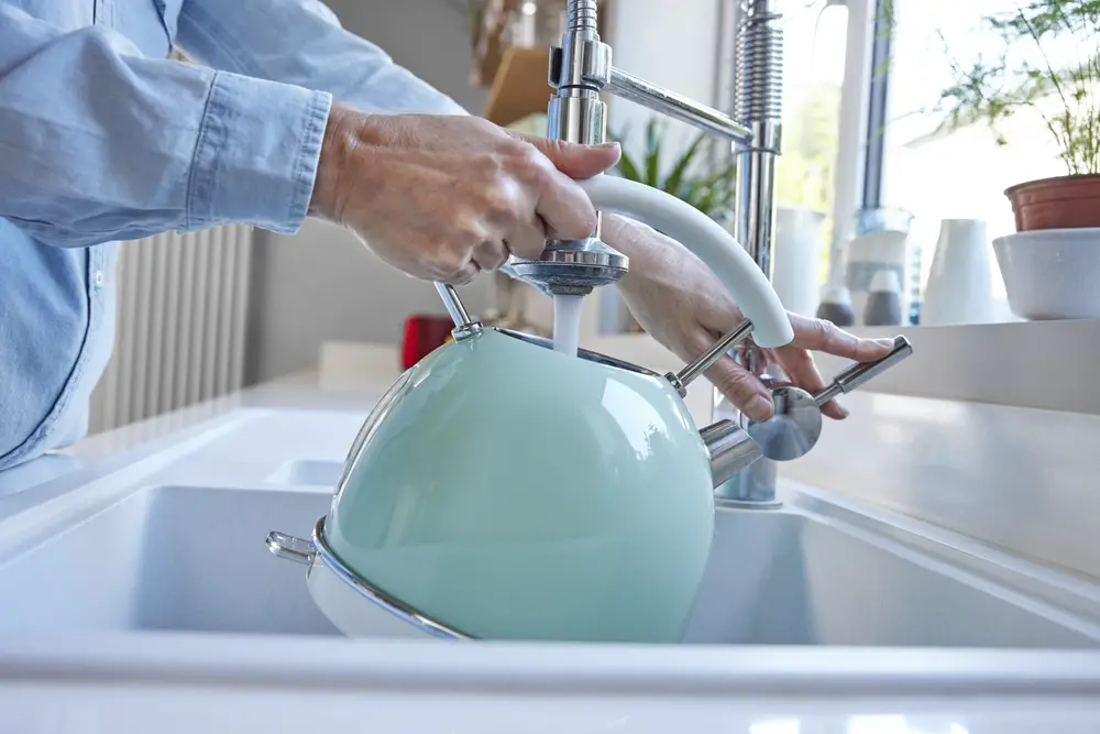 a-pair-of-hands-holding-a-green-kettle