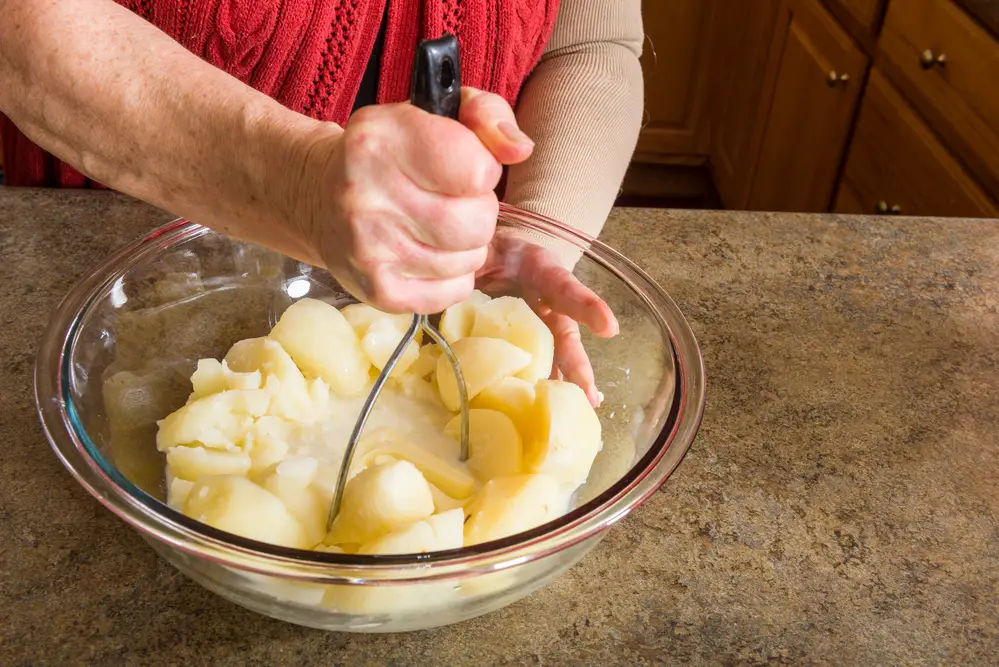 a-pair-of-hands-mixing-crushed-vegetable-with-milk-and-butter