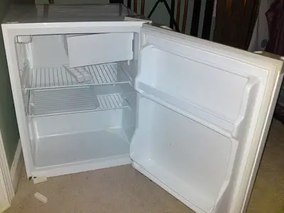 A small, newly cleaned refrigerator was opened.