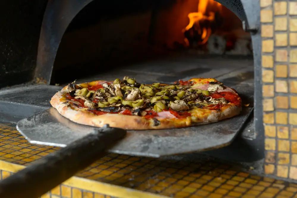 Fresh food on a shovel is putting out a traditional wood-fired stone fire place