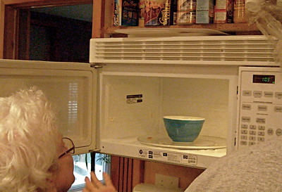 a woman heating food in a bowl using an electronic machine