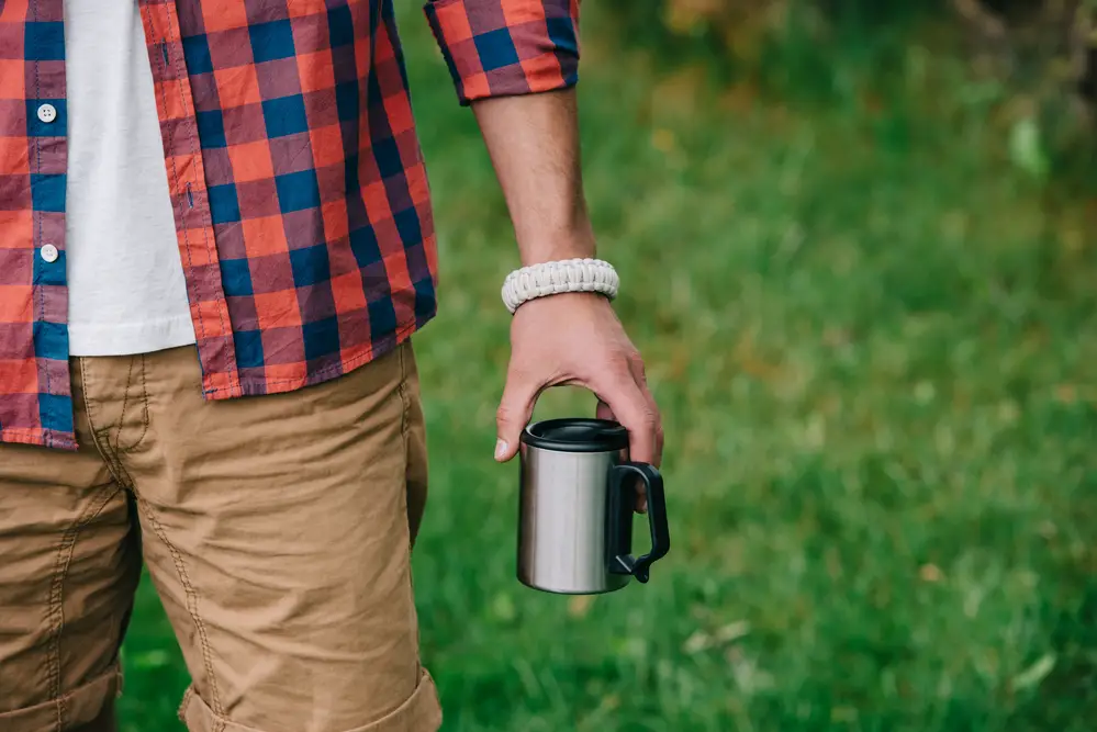 A man holding a stainless steel coffee cup