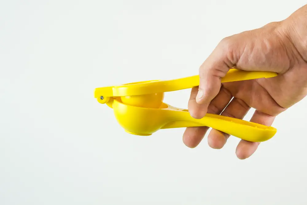 Hand holding a long handled manual juicer