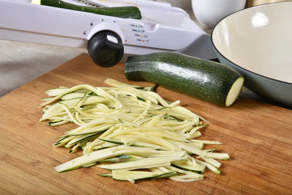 Fresh organic zucchini on a cutting board with a mandoline slicer