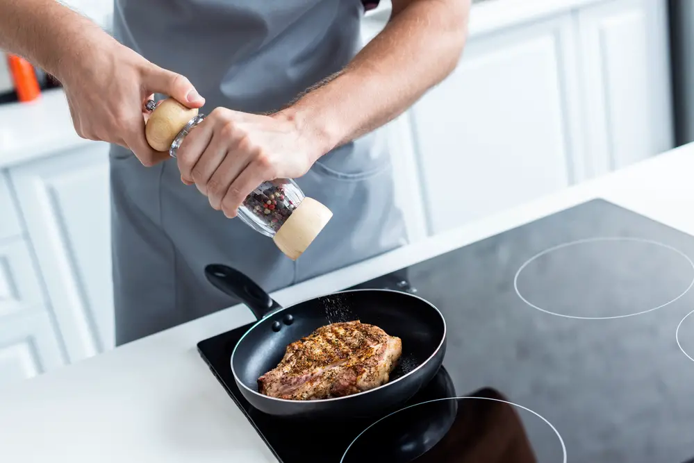 man seasoning the meat on non-stick cookware